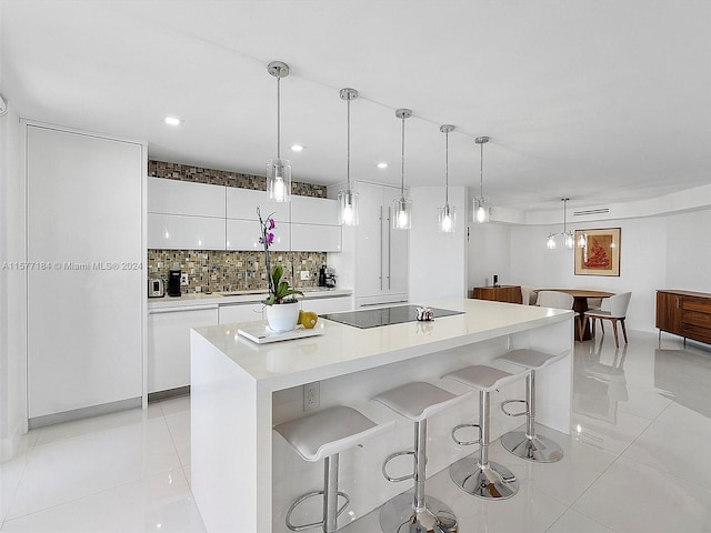 kitchen featuring white cabinets, a center island, decorative light fixtures, black electric stovetop, and tasteful backsplash