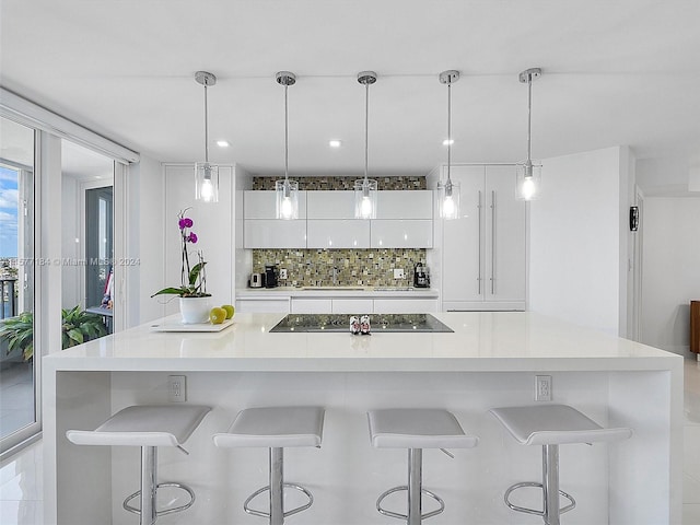 kitchen with white cabinetry, black electric cooktop, decorative light fixtures, and a large island