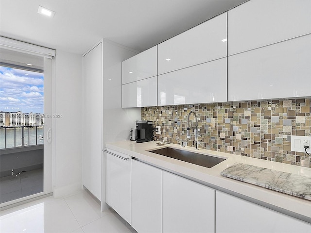 kitchen featuring sink, decorative backsplash, white cabinets, and light tile patterned flooring