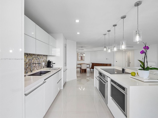 kitchen featuring hanging light fixtures, stainless steel appliances, sink, decorative backsplash, and white cabinetry