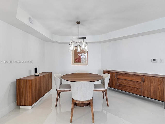 tiled dining area featuring a raised ceiling and a chandelier