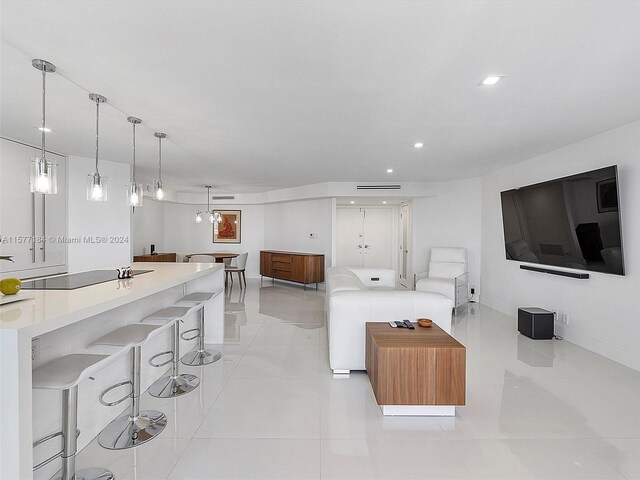 kitchen with black electric stovetop, light tile patterned floors, a kitchen breakfast bar, and hanging light fixtures