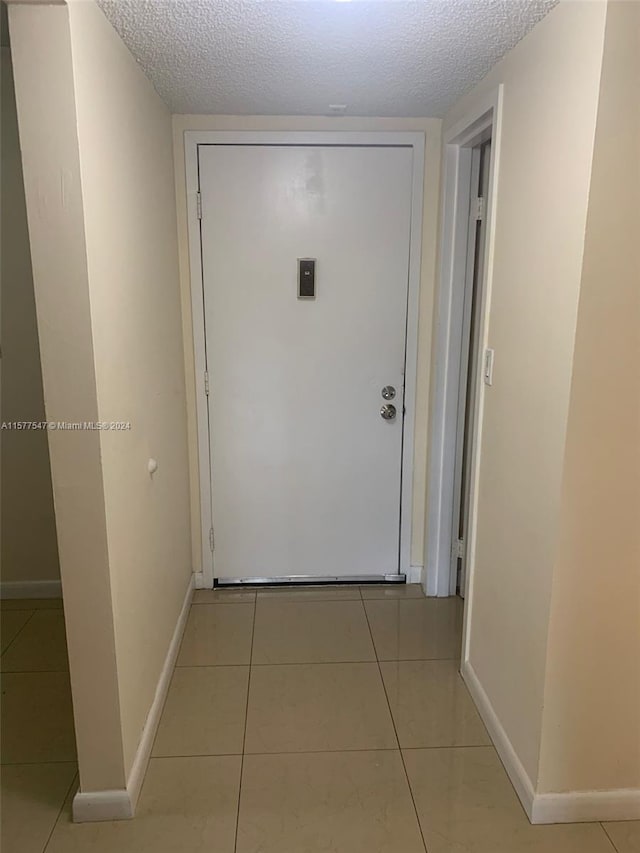 hall with light tile floors and a textured ceiling