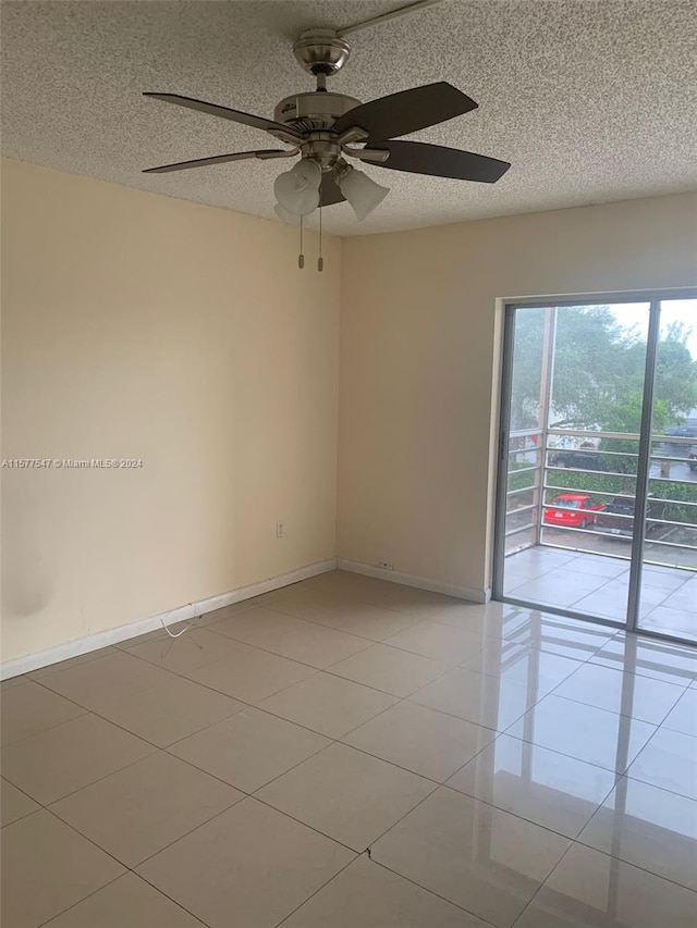 tiled empty room featuring ceiling fan and a textured ceiling