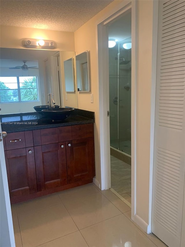 bathroom featuring walk in shower, tile floors, vanity, ceiling fan, and a textured ceiling