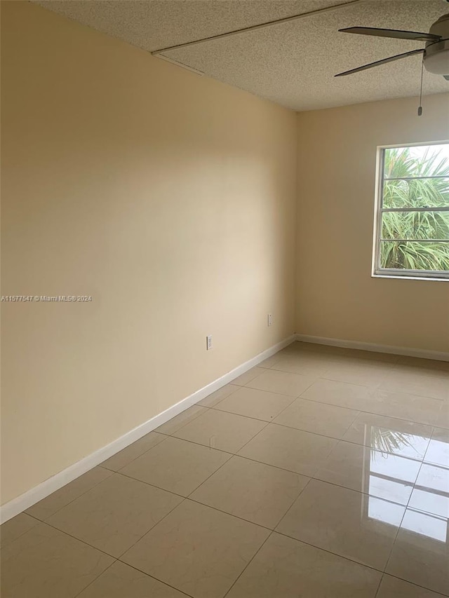 tiled spare room with ceiling fan and a textured ceiling