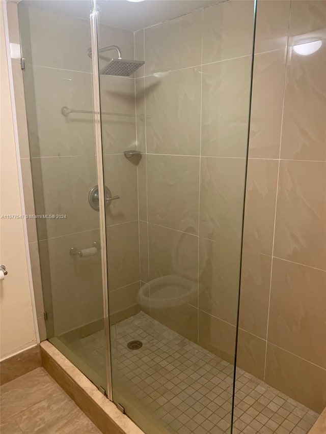 bathroom with walk in shower, toilet, and tile floors