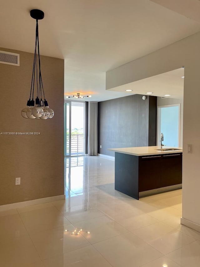 kitchen featuring dark brown cabinetry, pendant lighting, and light tile floors