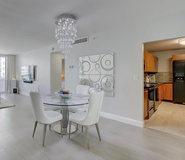 dining room with light hardwood / wood-style floors and a notable chandelier