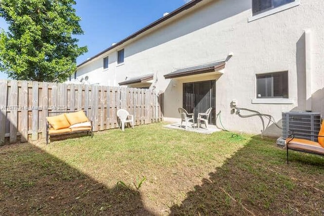 rear view of house with central AC unit and a lawn