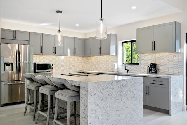 kitchen with a center island, light hardwood / wood-style floors, tasteful backsplash, decorative light fixtures, and stainless steel appliances