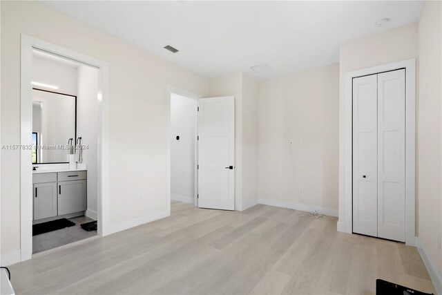 unfurnished bedroom with a closet, light hardwood / wood-style floors, and connected bathroom