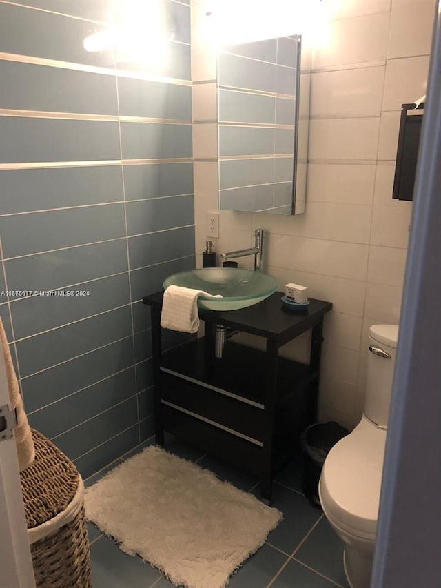 bathroom with tile walls, vanity, toilet, and tile flooring