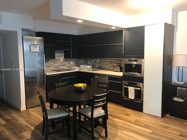 kitchen with sink, tasteful backsplash, stainless steel appliances, and light wood-type flooring