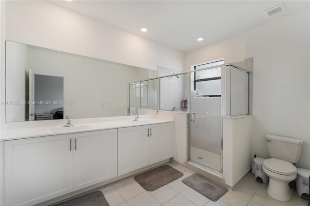 bathroom featuring tile patterned flooring, vanity, toilet, and a shower with door