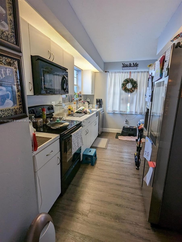 kitchen with hardwood / wood-style floors, sink, white cabinets, and black appliances