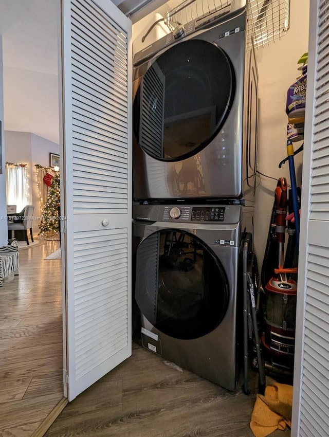 laundry room with hardwood / wood-style floors and stacked washer and dryer