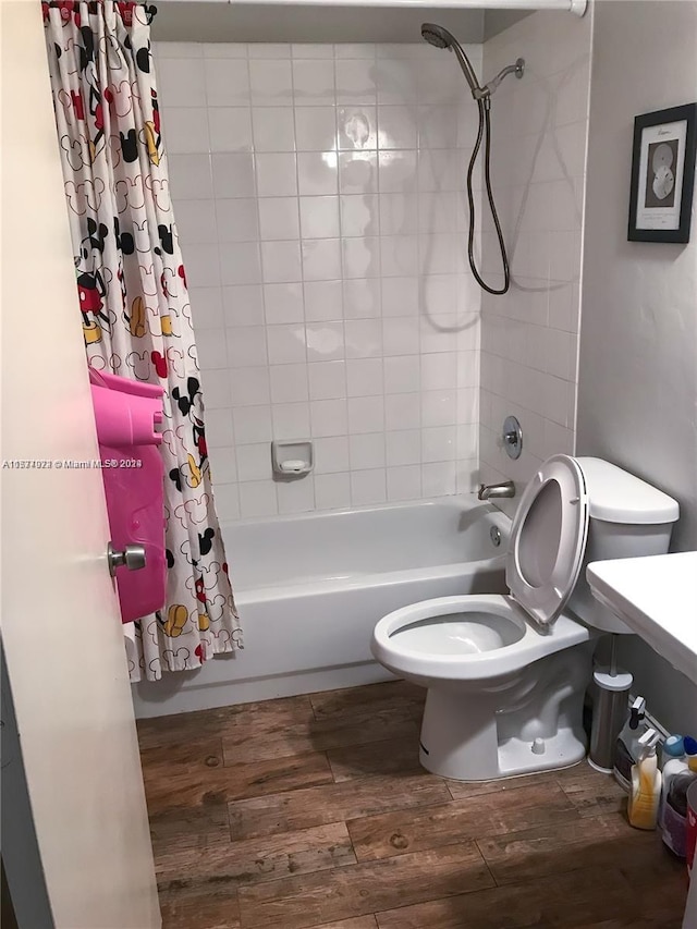 bathroom with hardwood / wood-style flooring, shower / bathtub combination with curtain, and toilet