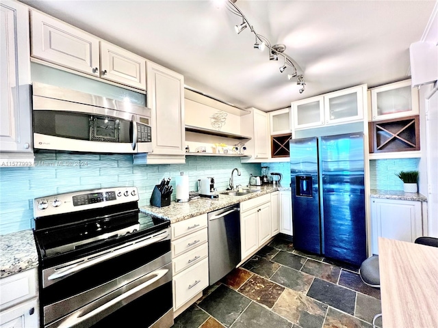 kitchen featuring white cabinets, tasteful backsplash, rail lighting, and stainless steel appliances