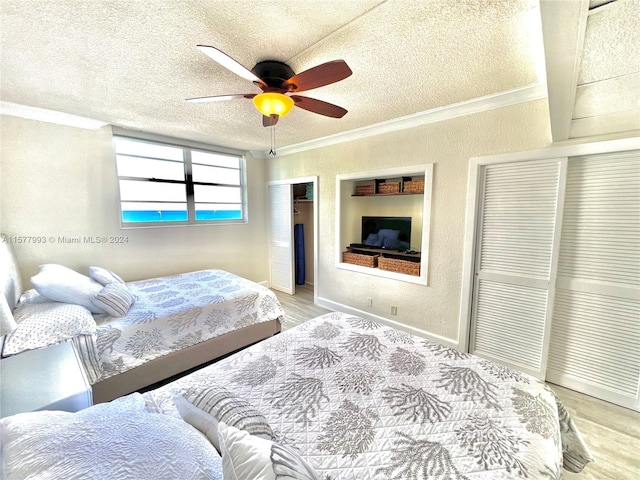 bedroom with ornamental molding, wood-type flooring, ceiling fan, and a textured ceiling