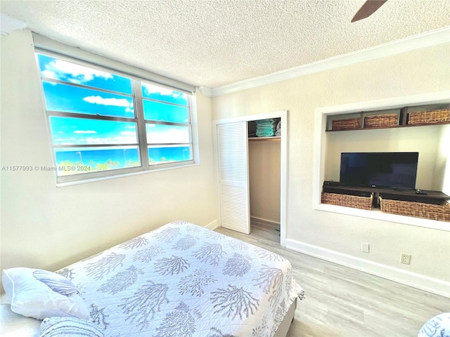 bedroom featuring ceiling fan, light wood-type flooring, and a textured ceiling