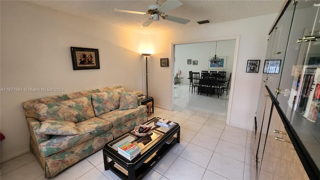 living room with a textured ceiling, ceiling fan, and light tile floors