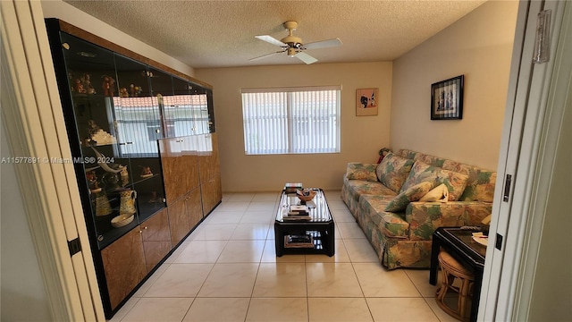 living room with a textured ceiling, ceiling fan, and light tile floors