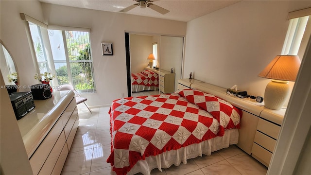 bedroom featuring ceiling fan, a closet, and light tile floors