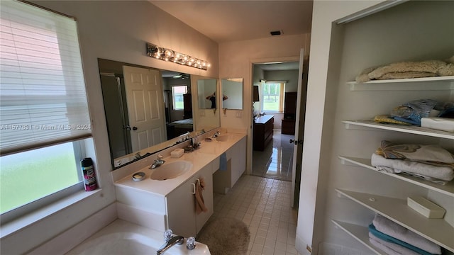 bathroom featuring a tub, tile floors, vanity with extensive cabinet space, and dual sinks