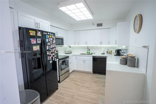 kitchen with backsplash, white cabinets, black appliances, and sink