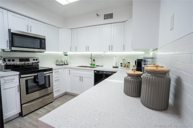 kitchen featuring white cabinets, sink, appliances with stainless steel finishes, and backsplash