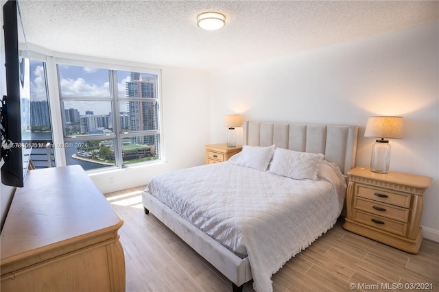 bedroom with light wood-type flooring and a textured ceiling