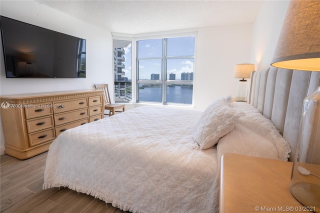 bedroom featuring a wall of windows, wood-type flooring, and a textured ceiling