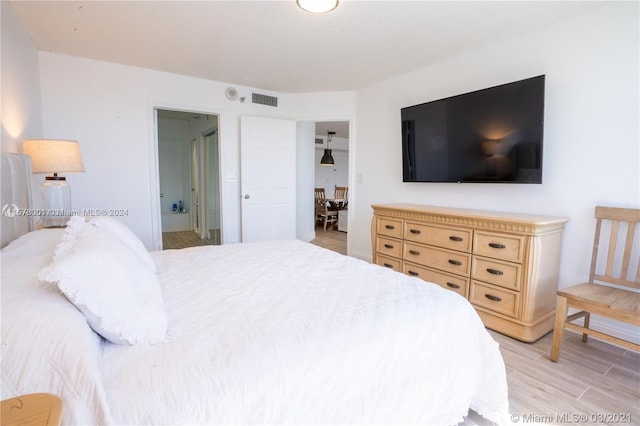 bedroom with light hardwood / wood-style floors and connected bathroom