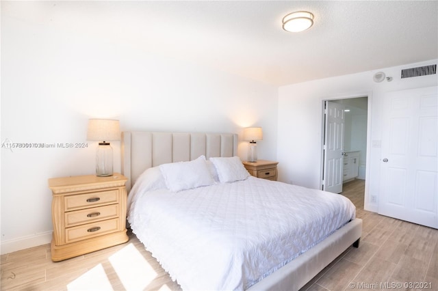 bedroom with hardwood / wood-style floors and connected bathroom