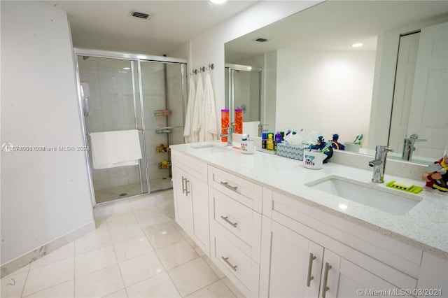 bathroom featuring dual bowl vanity, an enclosed shower, and tile floors