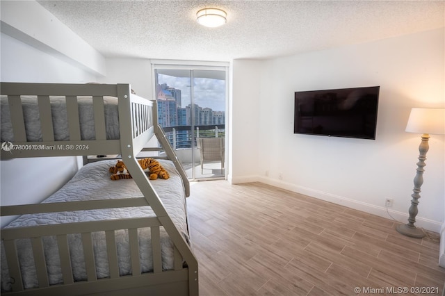 unfurnished bedroom with a wall of windows, light hardwood / wood-style flooring, and a textured ceiling