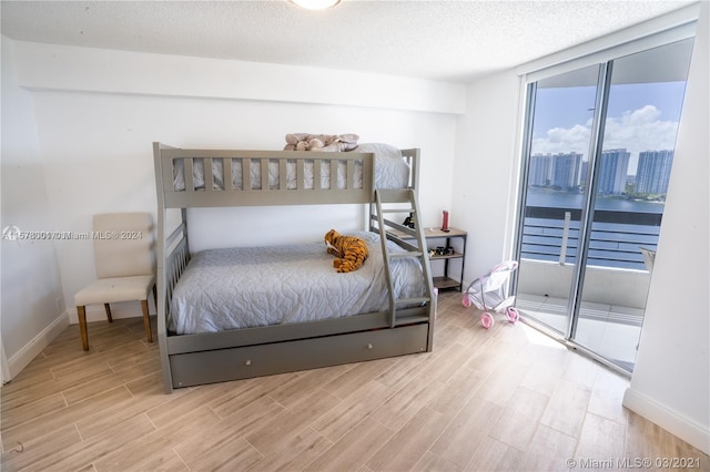 bedroom featuring floor to ceiling windows, a textured ceiling, and light hardwood / wood-style floors