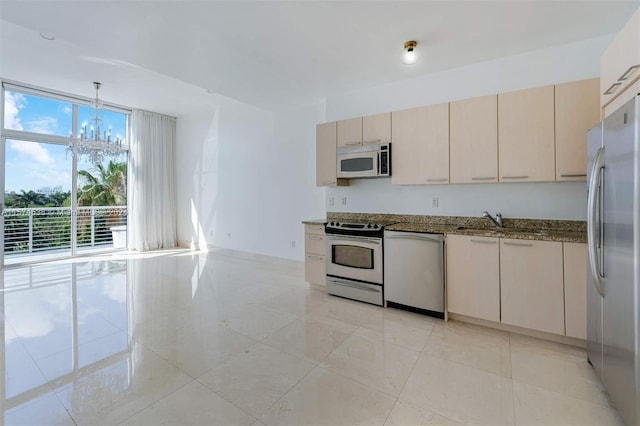 kitchen featuring sink, dark stone counters, stainless steel appliances, and light tile floors