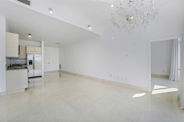 unfurnished living room with sink, a notable chandelier, and light tile floors