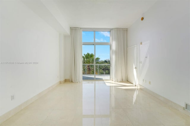 unfurnished room with floor to ceiling windows and light tile floors