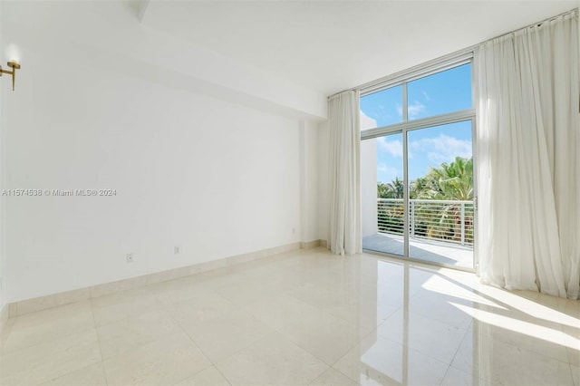 unfurnished room with a wall of windows and light tile floors