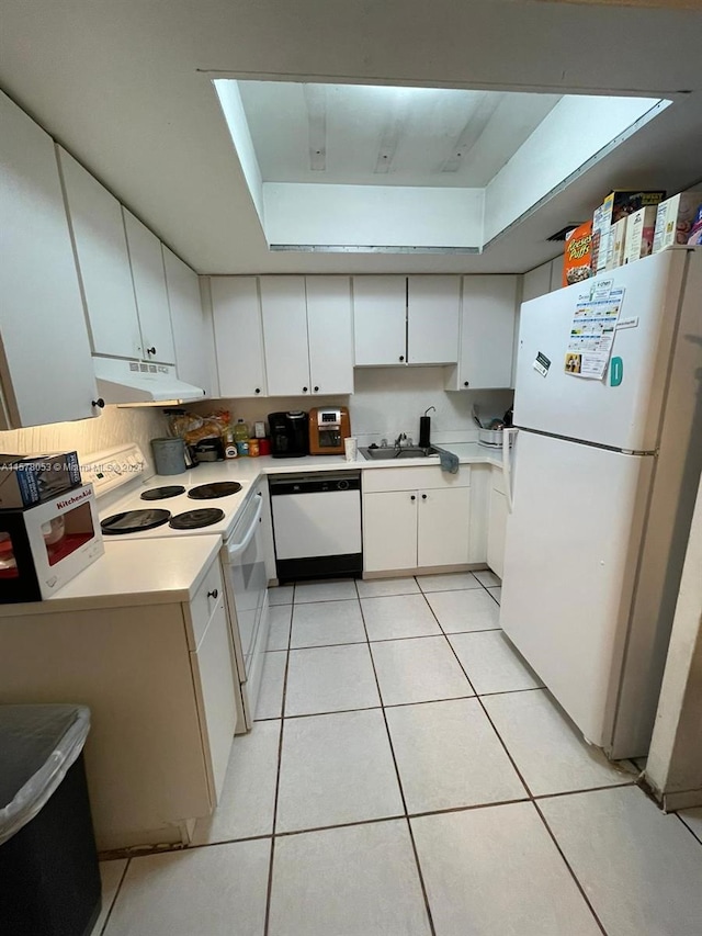 kitchen with white cabinets, white appliances, light tile floors, sink, and a raised ceiling