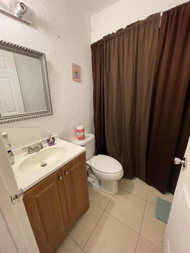 bathroom with toilet, tile flooring, and vanity