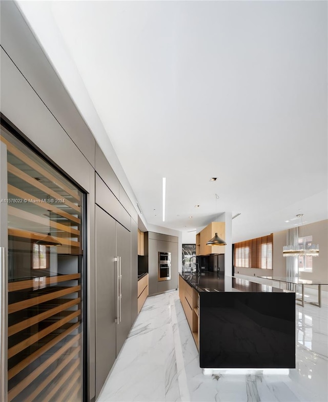 kitchen with light brown cabinets, oven, hanging light fixtures, and a spacious island