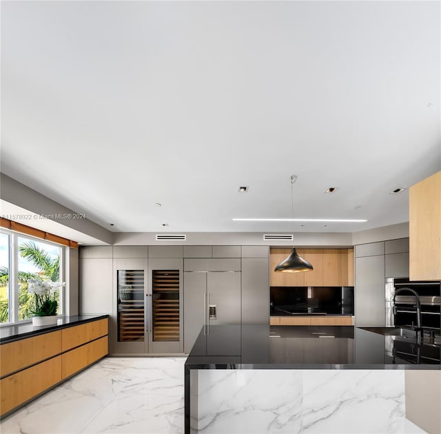 kitchen with stainless steel appliances, hanging light fixtures, and dark stone counters