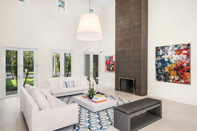 tiled living room with french doors, a high ceiling, and a fireplace