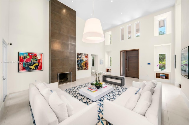 living room featuring light tile floors, a towering ceiling, and a tiled fireplace