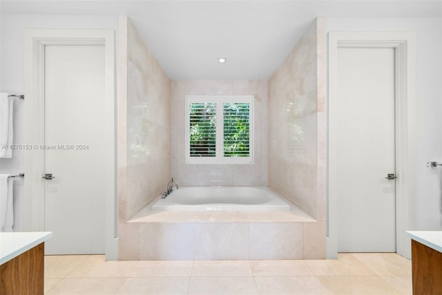 bathroom with tile flooring, vanity, and tiled bath