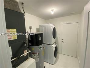 clothes washing area featuring stacked washer / dryer and water heater